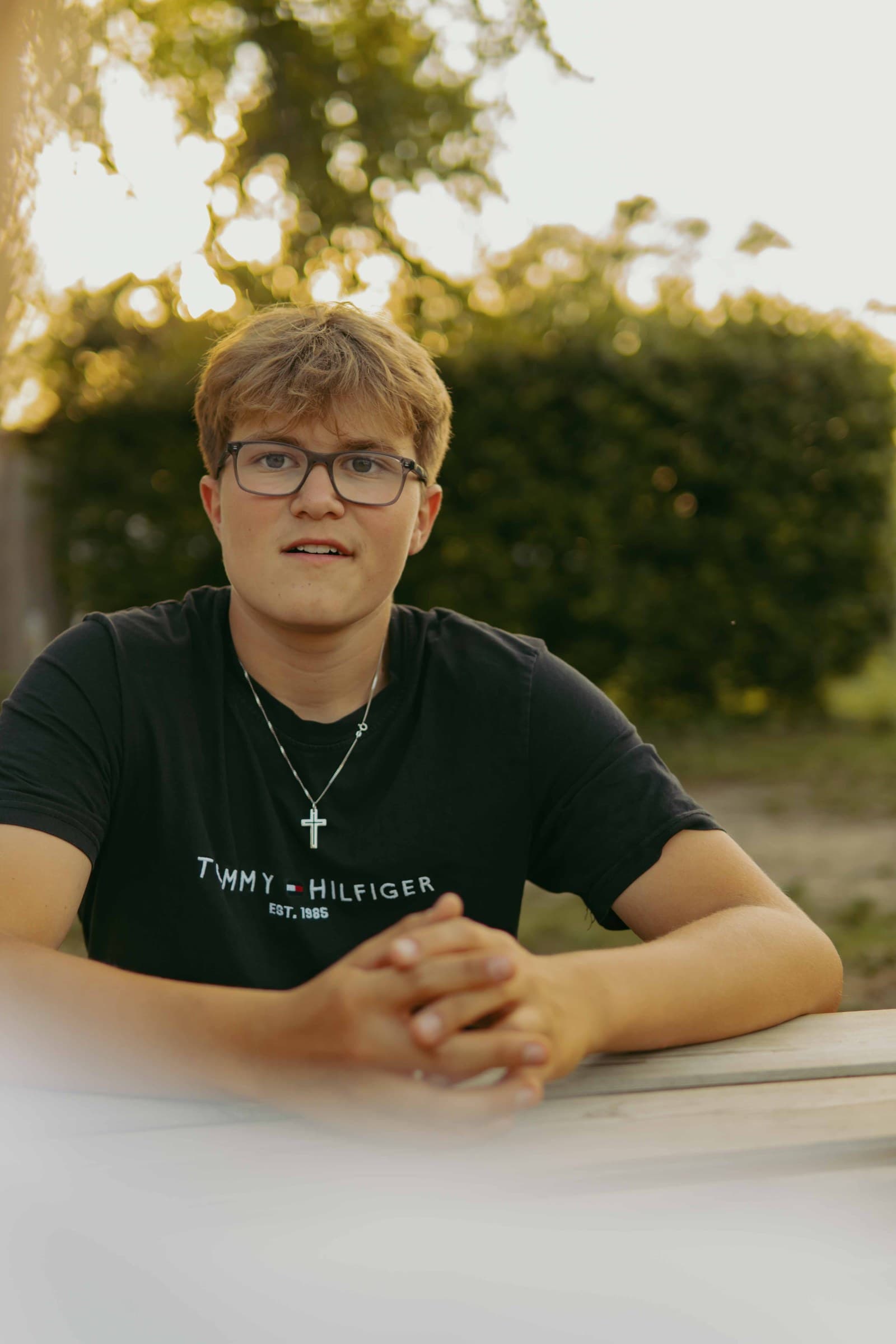 Jugendlicher mit Brille im Gespräch am Tisch im Abendlicht