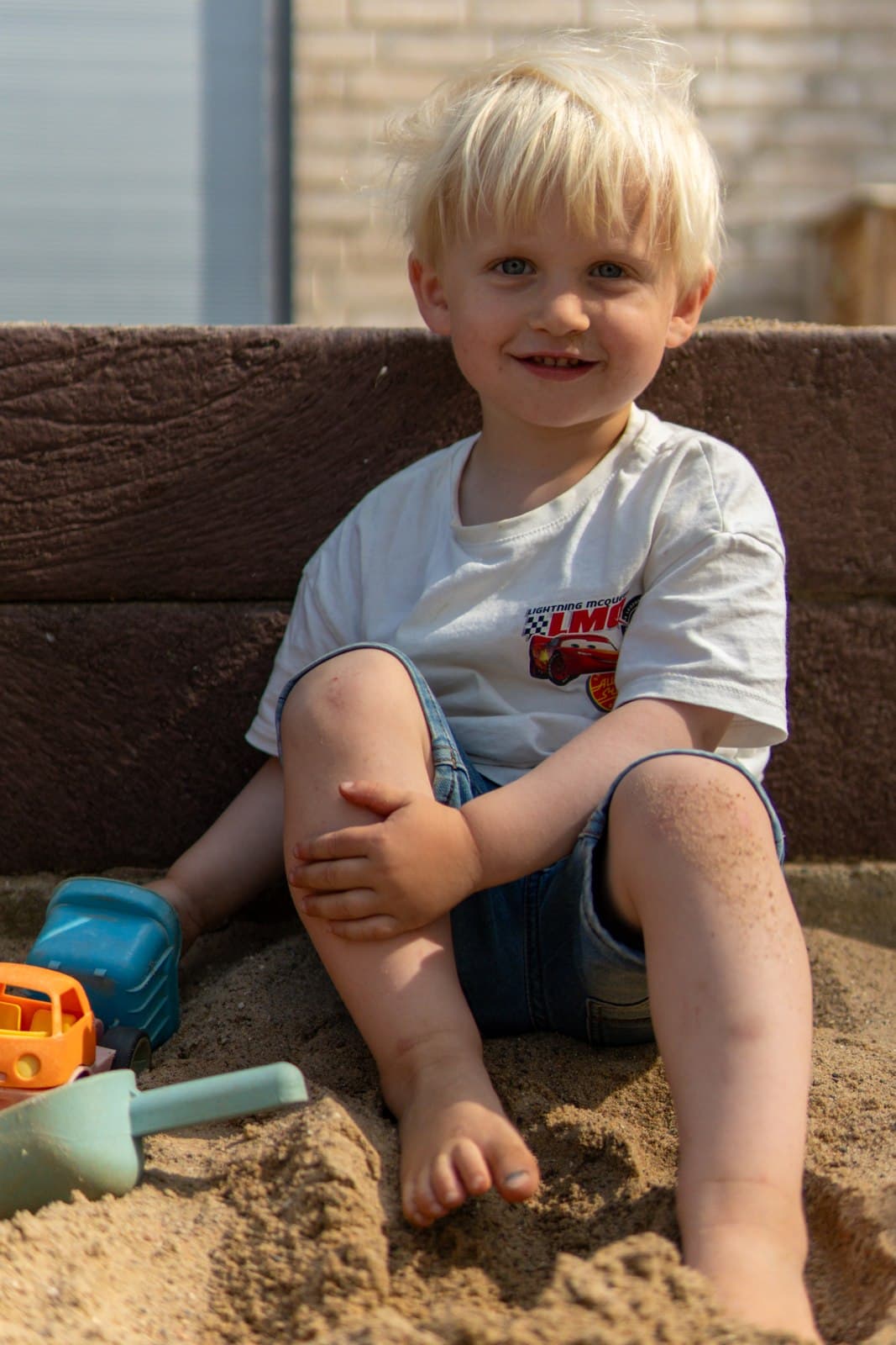 Ausgelassenes Lachen im Sand, umgeben von Spielzeug